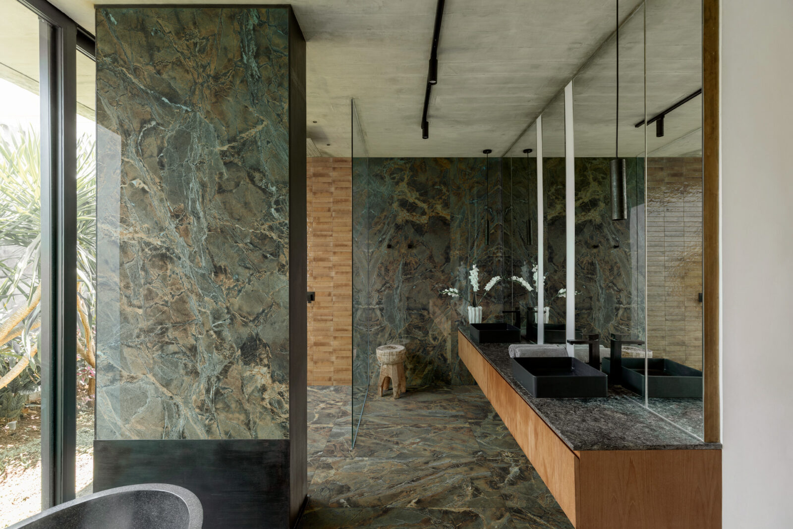 Dark bathroom with black marble-look tiles and brass fixtures